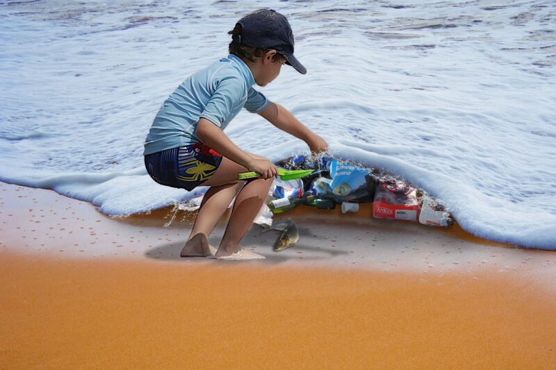 小男孩在撿拾海水裡的海洋垃圾